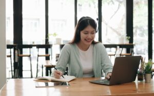 Asian woman wearing headphones study online watching webinar podcast on laptop listening learning