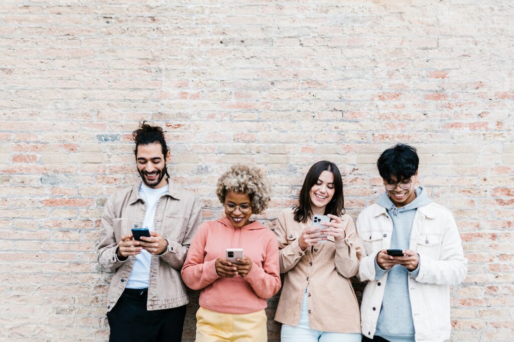 Four multiracial people using mobile phone outdoors