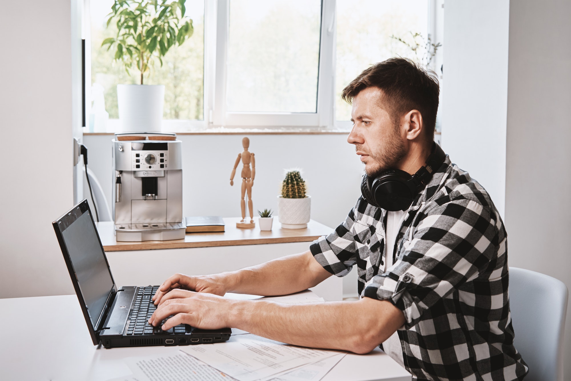 Man works remotely at home office with laptop